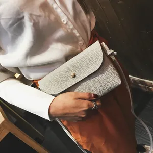 Mini white crossbody bag with lychee texture and gold metal buckle shown on a model
