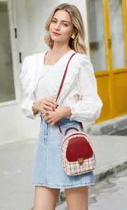 Mini sac à dos à carreaux avec garniture en cuir rouge et fermoir rotatif sur un mannequin