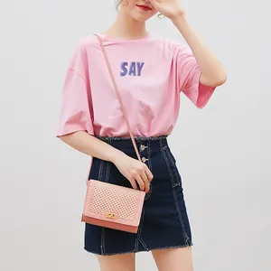 Pink mesh-textured crossbody bag with golden lock clasp on a casual fashion model
