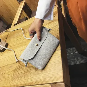 Light grey pebble leather mini crossbody bag with gold magnetic buckle and knotted strap