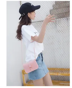 Petit sac bandoulière rose minimaliste avec boucle dorée présenté dans un décor de rue