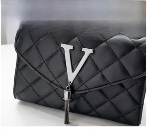 Détail du sac à main en cuir matelassé noir avec logo V argenté et pompon en métal