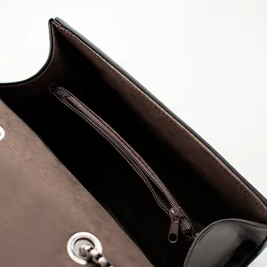Vue intérieure du sac à bandoulière en cuir noir avec doublure brune et poche zippée