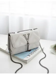Close-up of white quilted leather bag with V-shaped metal logo and chain strap detail