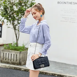 Sac à bandoulière matelassé noir avec chemise à rayures bleues et jupe blanche élégante