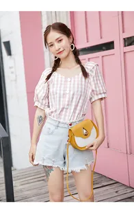 Detail of color-block saddle bag with teardrop lock paired with plaid summer top