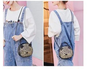 Detail of mini leopard print cat-ear crossbody bag with metallic zipper and slim shoulder strap
