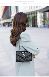 Détail du sac bandoulière matelassé noir avec logo V argenté et pompon élégant