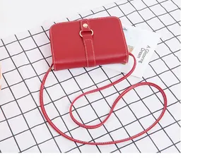 Détail du sac rouge à bandoulière avec surpiqûres blanches et boucle dorée sur tissu