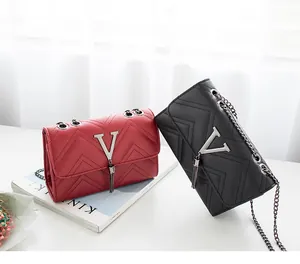 Close-up of V-quilted faux leather crossbody bags with metal logo and tassel fringe details