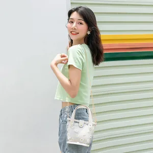 Bolso cubo transparente de PVC con estampado de margaritas, borde blanco y correa de cadena