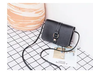 Détail du sac à bandoulière en cuir PU noir avec coutures blanches et boucle en anneau doré