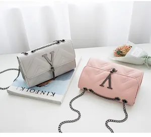 Detail of gray and pink crossbody bags with wavy stitching and V-shaped tassel charms