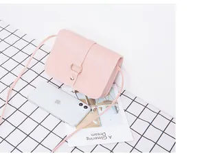 Détail d'un petit sac bandoulière rose avec boucle en métal et smartphone pour échelle