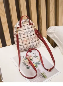 Détail du mini sac à dos à carreaux avec bretelles rouges et finitions dorées
