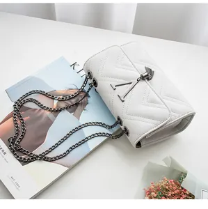 Detail of white quilted handbag featuring V-shape stitching and gray metal chain strap
