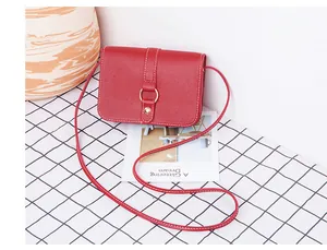 Détail du sac bandoulière rouge avec surpiqûres blanches et boucle circulaire dorée