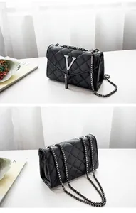 Détail du sac matelassé noir avec logo en V argenté et pompon pour un style chic
