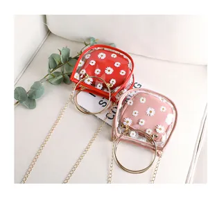 Détail du sac transparent en PVC avec pochette marguerites et poignées dorées