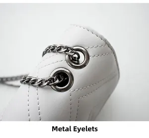 Detail of metal eyelets and silver chain strap on white quilted leather shoulder bag