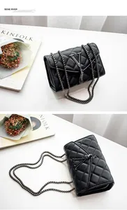 Détail du sac bandoulière matelassé noir avec logo V métallique et pendentif à franges