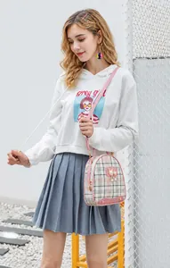Outdoor shot of a pink checkered mini bag with pearl charm and cat badge detail