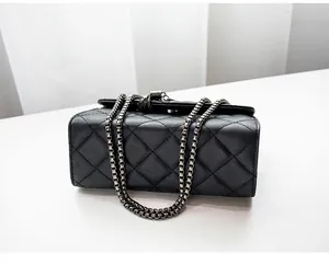 Détail du sac bandoulière noir matelassé avec bandoulière en chaîne métallique
