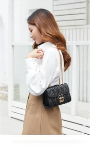 Close-up of black matelassé shoulder bag with golden square lock and chain strap