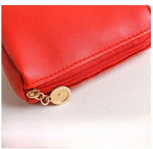 Détail de cuir rouge texturé avec coutures précises et fermeture éclair ronde dorée