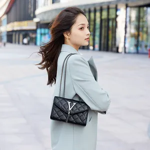 Sac bandoulière matelassé noir avec logo V argenté, pompon et chaîne métallique