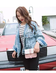 Outdoor lifestyle shot showing pink and beige crossbody bag with heart charm detail