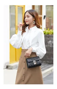 Outdoor lifestyle shot of a woman wearing a black quilted leather crossbody bag with chain