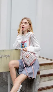 Detailed view of a pink plaid backpack with pearl charm and metal cat ornament