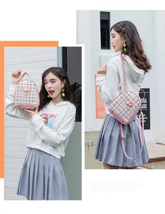 Pink plaid mini backpack with pearl cat charm shown in hand and on the shoulder