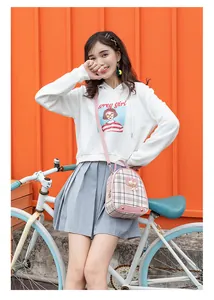Pink checkered mini backpack featuring cat metal charm shown in a trendy street setting