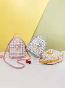Detailed view of plaid small handbags in pink, blue, and yellow with pearl cat charms