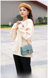 Detailed view of dark green plaid wool square bag with golden chain strap on female model