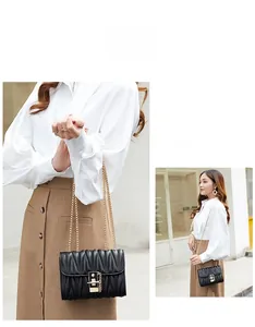 Detail view of black pleated quilted crossbody bag with gold lock and metal chain strap