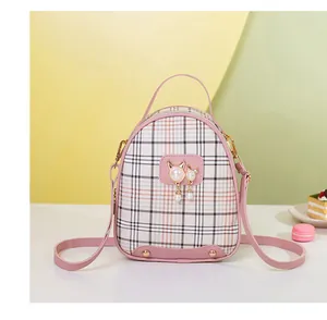 Detail of pink plaid mini backpack with pearl cat charm and protective base studs