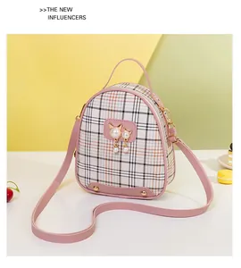 Detail of plaid crossbody bag with pink leather trim and pearl cat charm ornament