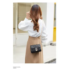 Fashionable black quilted chain bag with gold lock shown on model for a trendy look