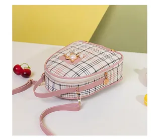 Detail of pink plaid crossbody bag with pearl decoration and golden metal cartoon charm