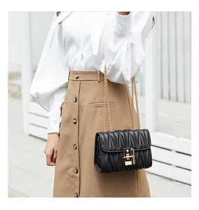 Detail of black matelassé pleated shoulder bag with gold square lock and chain strap