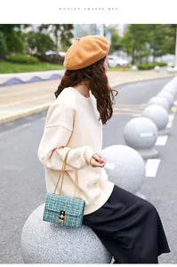Close-up of green plaid woolen square bag with golden chain and metallic buckle