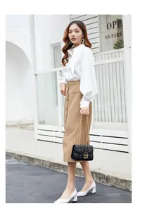 Fashionable black quilted chain handbag styled with a khaki skirt and white shirt