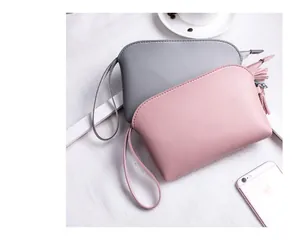 Schicke kleine Handtaschen in Rosa und Grau mit Quasten auf weißem elegantem Untergrund
