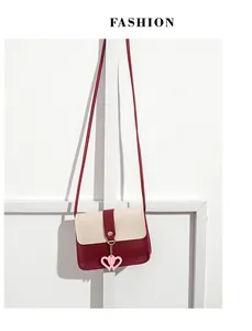 Detail view of mini two-tone crossbody bag with pink heart pendant and gold buckle