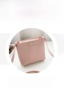 Detail of pink crossbody bag showing fine leather texture and metal logo hardware