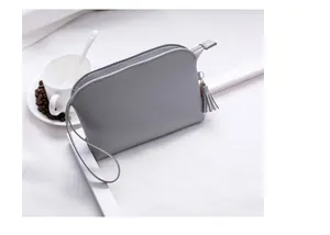 Details der grauen Muschel-Clutch aus PU-Leder mit Fransenquaste und Handgelenkschlaufe