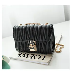 Detail of black matelassé quilted leather bag with gold chain and metal clasp